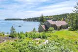 The property is surrounded by mature trees, and it offers striking waterfront views from its elevated granite perch.