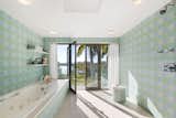 Wrapped in pastel tile, the primary bath has a large soaking tub and direct outdoor access.