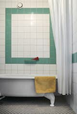 Green bathroom tile adds a playful splash of color to the otherwise minimalist home.