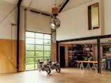 The workshop interiors emphasize function, with polished concrete slab floors and 35-foot-high ceilings to accommodate large projects and gatherings. The disco ball, set to spin via a smartphone app, can be lowered with an industrial winch and is visible from the overhead studio suite through a peek-a-boo window.