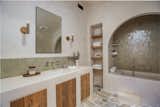 The home’s arch motif continues in the bathroom, where stone floors, a custom vanity, built-in shelving, and a large tadelakt soaking tub await.&nbsp;