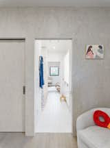 View from children's bedroom into white tiled bathroom and nursery. 