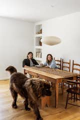 Couple sits at antique wood table under pendant lamp with dog walking by in foreground.