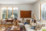 Children play in living room with large windows looking out into forest.