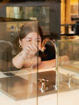 Woman examines faucet in light brass finish. 