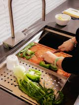 Woman cuts vegetables at composite workstation sink. 