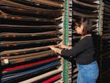 Woman rifles through shelves containing sheets of laminate countertops in warehouse. 