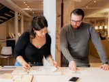 Woman and man examine selection of tile samples in showroom. 