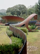 Beyond the main structure, a series of sculptures trail off into a garden with terraced lawns and ponds.  Photo 8 of 8 in One Night in a Kaleidoscopic, Snake-Shaped Apartment Complex Near Mexico City