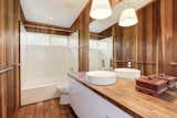 The primary en suite bath is wrapped in teak and offers a dual vanity and large shower.