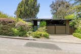 Attractively understated from the street, the home sits surrounded by soaring trees and mature native landscaping. The sizable cement driveway leads to the multi-car garage.