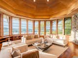 The living room is lined with cedar from floor to ceiling, and it features a wall of windows overlooking the Hudson River and a custom stone fireplace.