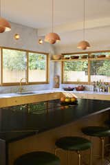 Verner Panton–designed pendants from A+R hang in the kitchen, which also features counter stools from BassamFellows. "Because of the oak and the brass fixtures, it feels more bespoke than your average kitchen," says Bestor, who also designed the slatted fence outside.
