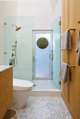 To maximize the feeling of space in the primary bathroom, Bestor decided to raise the ceiling up to the roofline. "It feels special and spacious even though it doesn’t take up a lot of square footage," she says. Of the door to the rear deck, David says, "You feel like you’re outside when it’s open." The wall tile is from Sonoma Tile.
