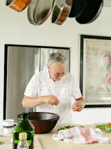 James, an accomplished cook who enjoys devising menus for dinner parties, preps a meal in the kitchen, which is outfitted with custom maple cabinets, Caesarstone countertops, Samsung appliances, and an enamel cast-iron sink from Kohler.