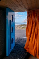 View of beach on the Canary Islands through blue door with round windows and orange curtain