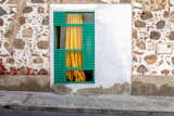 Window with green-blue frame, yellow curtain set into concrete addition to stone wall in Lanzarote, the Canary Islands