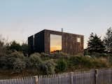 House clad in black-stained wood with two-story, double-height window in Cayeux-sur-Mer, a beach town in Normandy, France