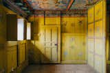 Room with light wood floors, peeling yellow walls painted with flowers, ceiling with blue and red orange murals of fantastical creatures in Ogyen Choling, a fortress-village in Bhutan