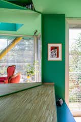 Large mirror reflects arm chairs upholstered with red velvet in home with green walls and ceilings in Turin, Italy