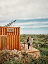 Man paints on wood deck outside wooden tiny home in the rolling landscape of Sintra, Portugal