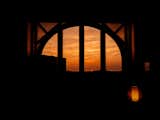 Arching wood-framed window in wooden tiny home in Sintra, Portugal, silhouetted by sunsent