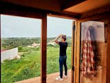 Man stands on wood deck outside wooden tiny home in the rolling landscape of Sinatra, Portugal