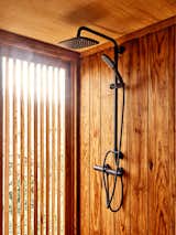 Wood shower stall with black fixtures in wooden tiny home in Sintra, Portugal