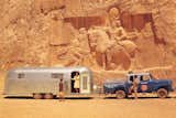 Wally Byam's Caravan Around the World is photographed with pickup truck towing Airstream outside monumental relief carving in desert cliff