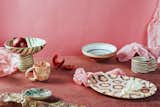 Horezu Romania striped and floral ceramic chalice bowl, marbled mug, trinket dish, bowl, oval platter, and brown and white striped mug made by Henry Holland, Silt Clay, Morgan Levine, and Casa de Folklore photographed with pink backdrop