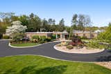 A paved circular drive slices the lush landscaped lot to lead to the stone-clad residence.