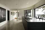 The kitchen is anchored by an expansive black island, which pops against the crisp white walls and polished concrete floors.