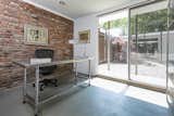 The light-filled office presents a similar aesthetic as to the main residence, complete with exposed brick walls, polished concrete floors, and large sliding glass doors.
