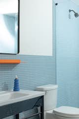 Maldonado partnered with Daltile to use matte one-inch keystone tile in a different tone for each bathroom, and suite 302 features a blue color. The orange surface is by Shelfology, and the soap bottle is Cloud 9 Clay.  Photo 7 of 17 in 17 Modern Bathroom Wall Ideas from At Yowie Hotel, an Overnight Stay Is Also a Crash Course in the Best Design You’ve Never Heard Of