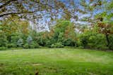 The backyard holds a large lawn fringed by mature trees and verdant landscaping.