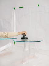 Clara Jorisch attaches glass top of coffee table to chunky transparent in Montreal workshop.