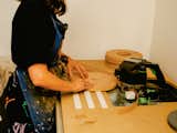 Adi Goodrich, founder of Sing Thing, applies a veneer to laminate wood disk in Los Angeles workshop.