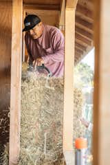 A builder sculpts a bale with his chainsaw so it stacks evenly. Johnson says that building the home with straw was as cost-effective as wood framing would have been, but thinks the method will only become less expensive as more contractors adopt the building style.