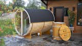 Redwood Outdoors barrel panorama sauna with black asphalt roof shingles and cedar-sided Alaskan Cold Plunge tub sits outside home. 