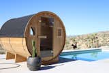 Redwood Outdoors barrel panorama sauna sits beside concrete pool in desert.
