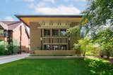 The home's overhanging roof is trimmed with copper, adding a subtle pop of color against its otherwise neutral, brick-clad facade.