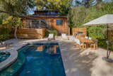 The lush backyard features a sparkling pool, an outdoor kitchenette, and a spacious dining area.