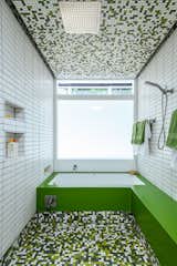Green and white tiled bathroom with large frosted translucent window in midcentury internationalist home in Wyomissing, Pennsylvania by Muhlenberg Brothers and renovated by Kevin Yoder and Louise Cohen.