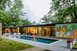 Large pool outside brick and glass facade of home in Wyomissing, Pennsylvania midcentury internationalist home by Muhlenberg Brothers and renovated by Kevin Yoder and Louise Cohen.
