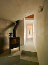 Hallway with concrete floor and woodburning stove in home by Andrew Frederick in Owls Head, Maine.
