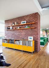 Brick partition with USM Modular yellow metal cabinets storing record and books, and medium-toned shelves and flooring  in Philip Johnson Wolf House in Newburgh, New York, renovated by Jiminie Ha and Jeremy Parker.