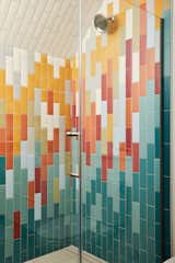 Colorful turquoise, red, and yellow tile in shower booth with glass doors in ADU in Saint Paul, Minnesota, by Christopher Strom Architects.