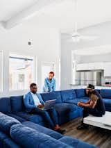 The living area provides space with blue wraparound sofa and white coffee table  for First 72+’s executive director, Troy Glover, economic empowerment manager Meagan Jordan, and Delone to meet in The Ben Smith Welcome Home Center in New Orleans, Louisiana, by OJT.