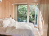 Pine-clad bedroom with bed and white bedding in aux box model 240 prefab prefabricated home.