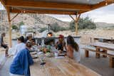 a group of friends eating dinner sitting under the pergola